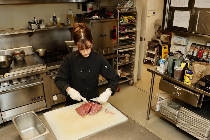 Paula Baker slices up steak, which was the main course for the Kiwanis Club luncheon held at CBH Feb. 20. BILL SHULL PHOTO